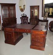 Front: double-sided, large partner desk with side return with soft maroon leather inserts. Rear L-R: Large display unit, valet stand, corner bookcase and filing cabinet, all in rose mahogany stain finish.
